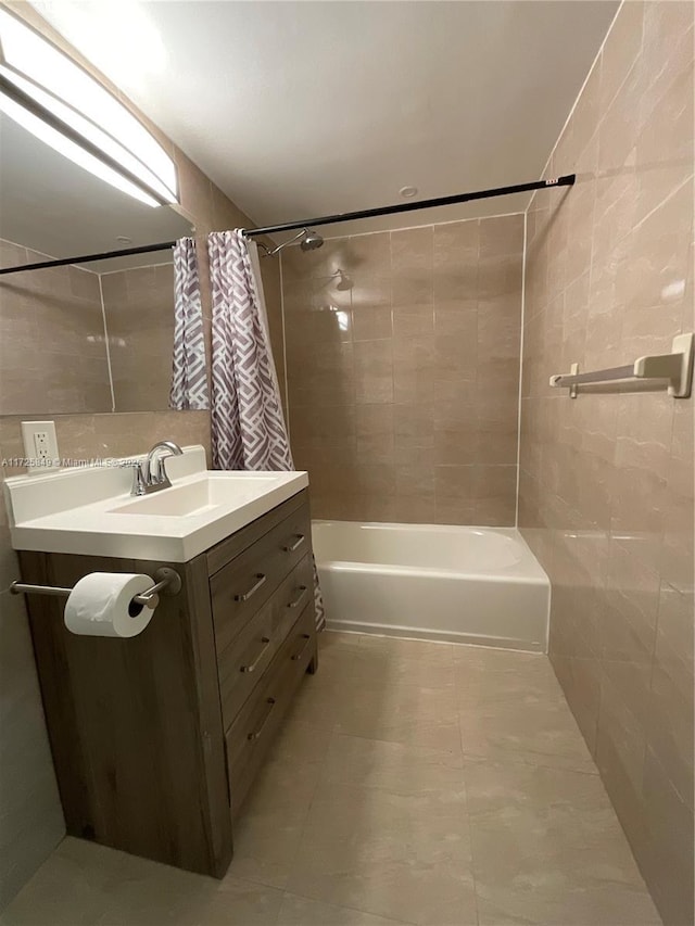 bathroom featuring tile walls, shower / bathtub combination with curtain, and vanity