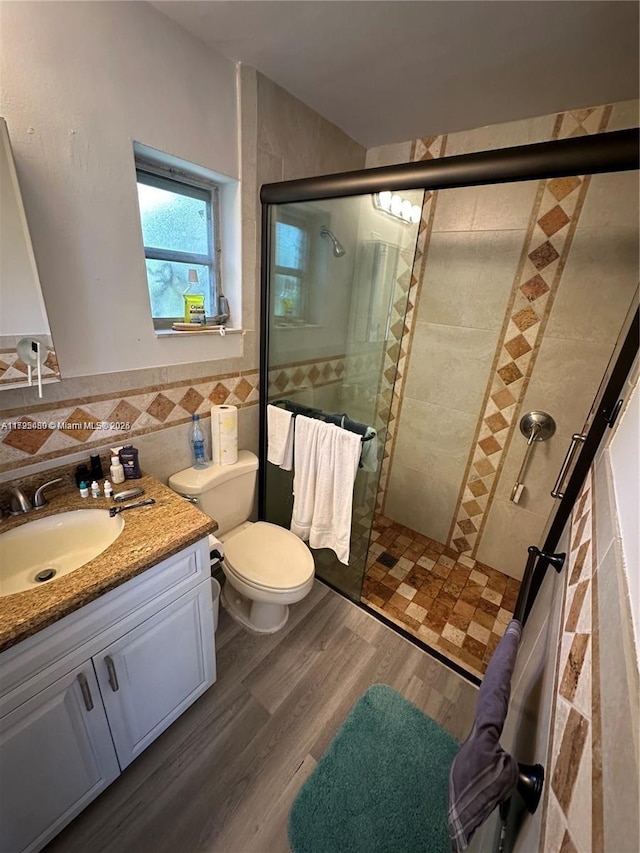 bathroom featuring toilet, walk in shower, hardwood / wood-style floors, tile walls, and vanity