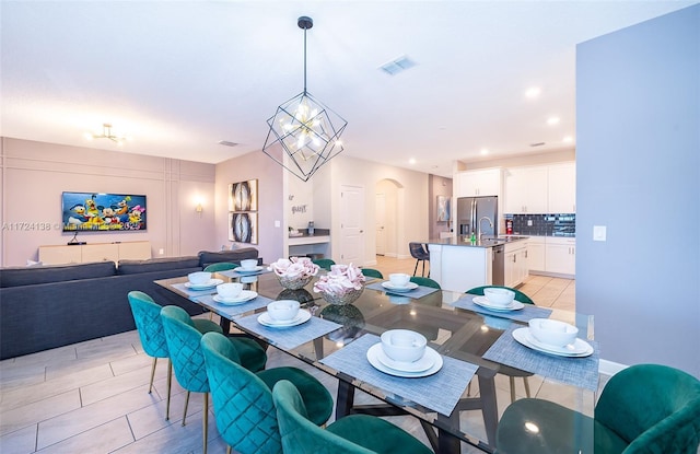 dining room featuring sink, an inviting chandelier, and light tile patterned floors