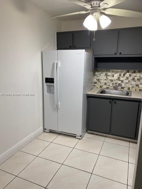 kitchen featuring ceiling fan, decorative backsplash, sink, light tile patterned floors, and white fridge with ice dispenser