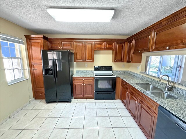 kitchen with sink, black dishwasher, a healthy amount of sunlight, and light stone countertops