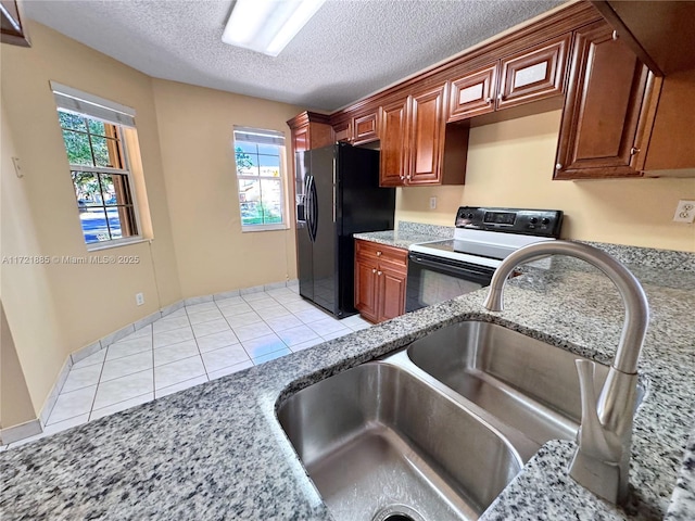 kitchen featuring light stone countertops, a textured ceiling, light tile patterned floors, black appliances, and sink