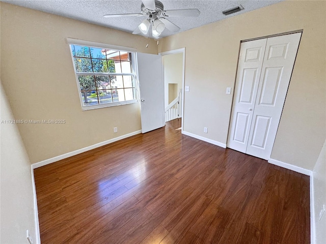 unfurnished bedroom with a closet, a textured ceiling, ceiling fan, and dark hardwood / wood-style floors