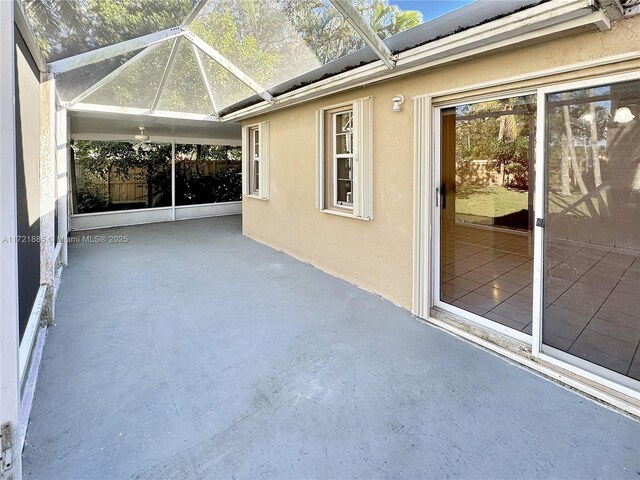 view of patio / terrace featuring ceiling fan and glass enclosure