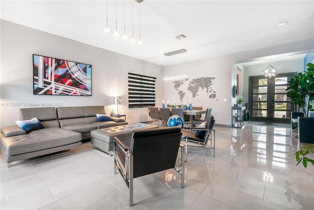 living area with an inviting chandelier, light tile patterned floors, visible vents, french doors, and baseboards