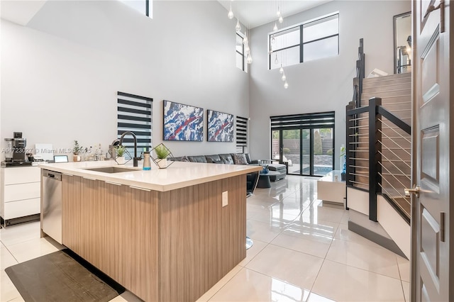 kitchen featuring open floor plan, light tile patterned floors, a high ceiling, modern cabinets, and a sink