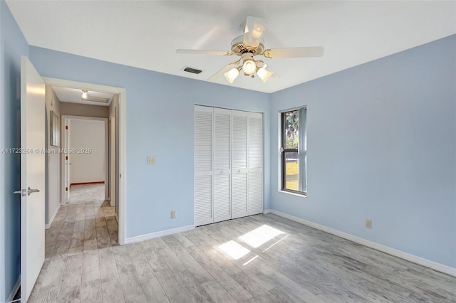 unfurnished bedroom featuring ceiling fan, light wood-type flooring, and a closet