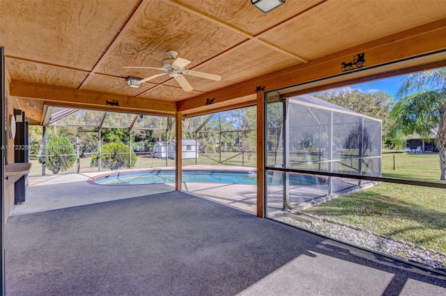 view of pool with a yard, glass enclosure, a storage shed, and a patio area