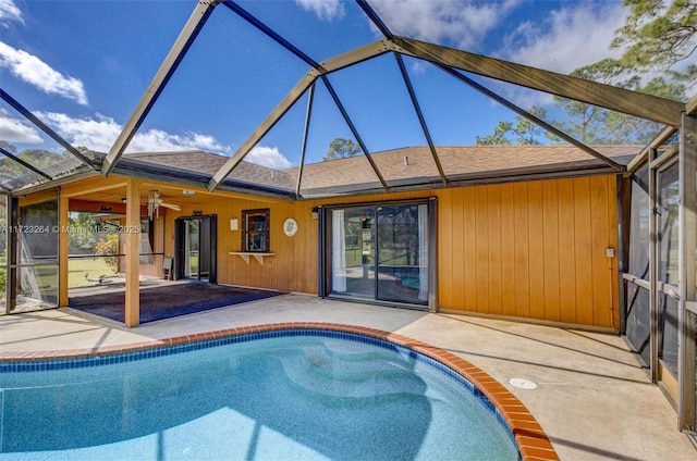 view of swimming pool featuring ceiling fan, glass enclosure, and a patio