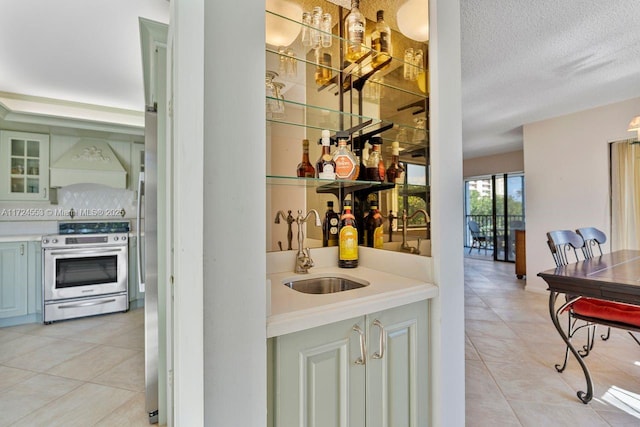 bar featuring stainless steel electric range, light tile patterned floors, a textured ceiling, custom range hood, and sink