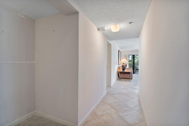 hall with a textured ceiling and light tile patterned flooring