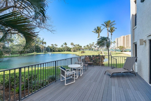 wooden terrace with a water view and a lawn