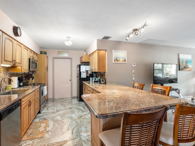 kitchen featuring appliances with stainless steel finishes, kitchen peninsula, a breakfast bar, and sink