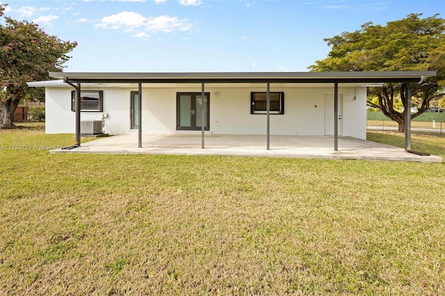 back of property with central AC unit and a yard