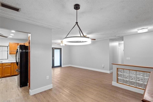 interior space featuring ceiling fan, french doors, a textured ceiling, and light hardwood / wood-style floors