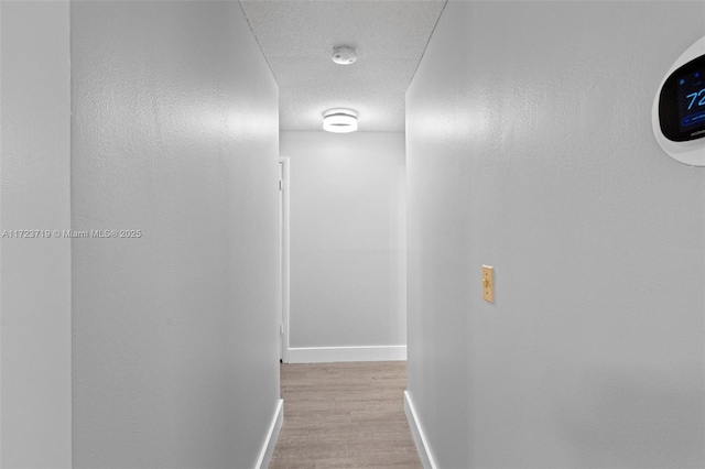 corridor featuring light wood-type flooring and a textured ceiling