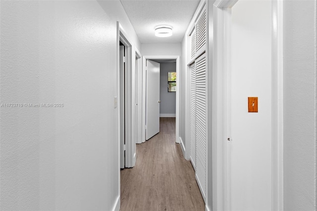 hall with a textured ceiling and light hardwood / wood-style floors