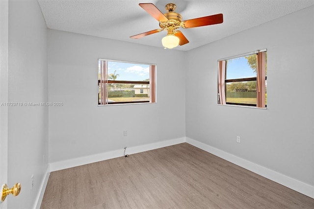 spare room with a textured ceiling, ceiling fan, and light hardwood / wood-style flooring