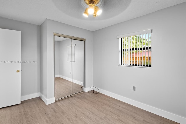 unfurnished bedroom with a textured ceiling, ceiling fan, a closet, and light hardwood / wood-style floors