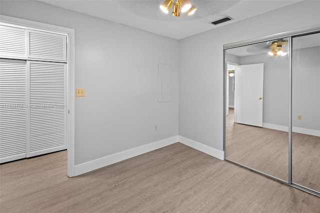 unfurnished bedroom featuring a closet, electric panel, a textured ceiling, and light hardwood / wood-style flooring