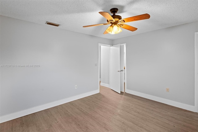 empty room with hardwood / wood-style flooring, a textured ceiling, and ceiling fan