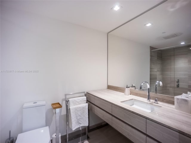 bathroom with a shower with shower door, vanity, and toilet