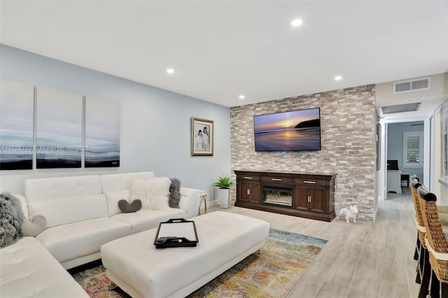 living room with light wood-type flooring and a large fireplace