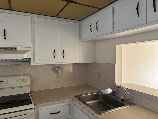 kitchen with sink, white cabinets, decorative backsplash, and electric range