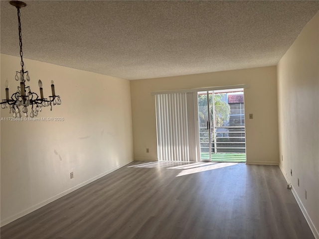 unfurnished room featuring a textured ceiling, a notable chandelier, and dark hardwood / wood-style floors