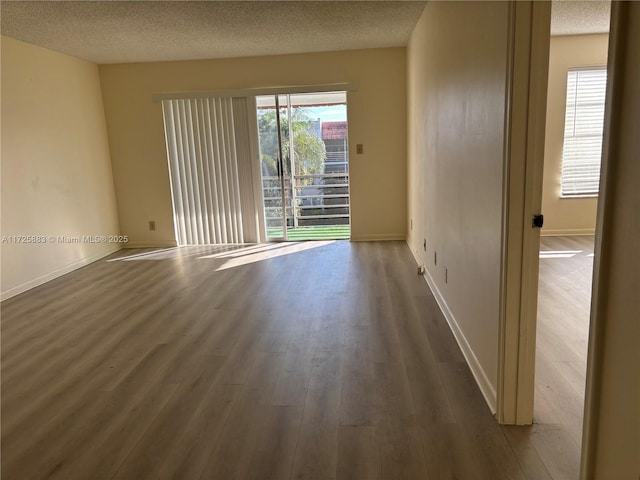 unfurnished room with dark wood-type flooring and a textured ceiling