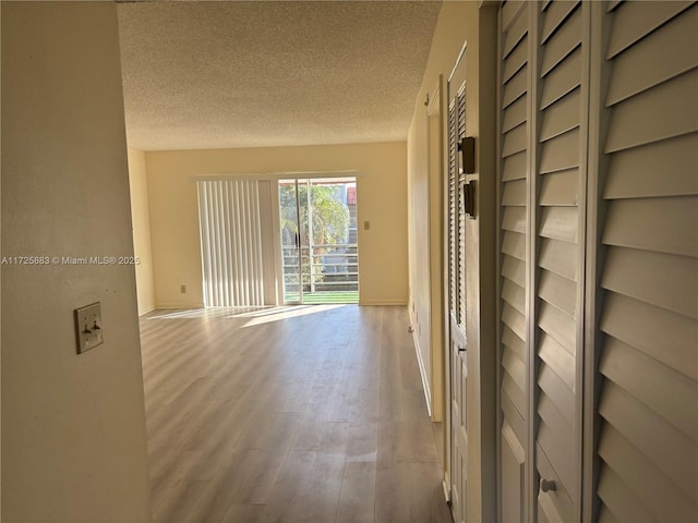 hallway featuring a textured ceiling and light hardwood / wood-style flooring