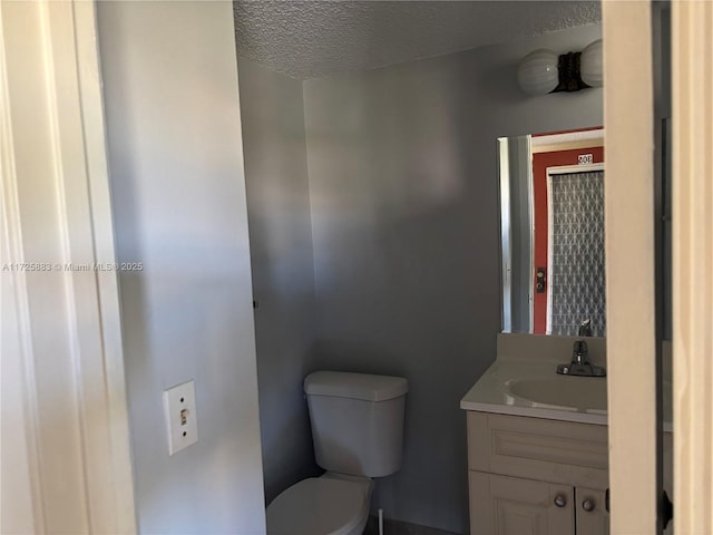 bathroom with toilet, vanity, and a textured ceiling