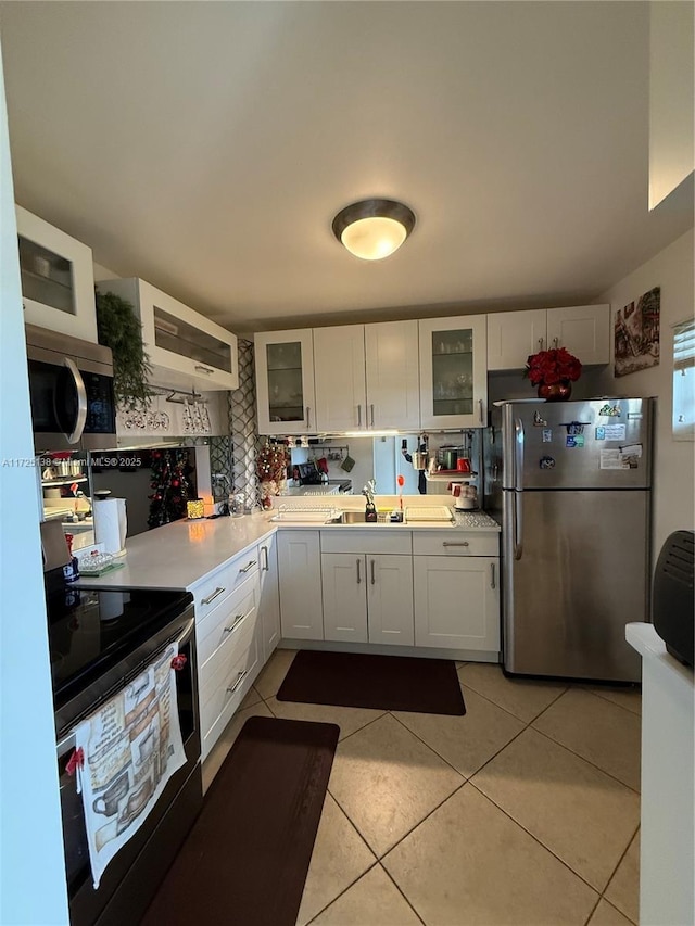 kitchen featuring sink, light tile patterned flooring, white cabinetry, and appliances with stainless steel finishes