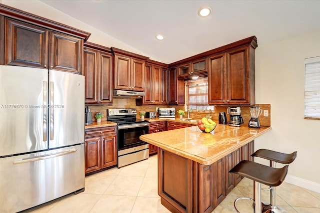 kitchen with sink, light tile patterned floors, kitchen peninsula, a breakfast bar, and appliances with stainless steel finishes