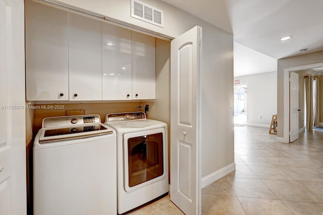 washroom featuring cabinets, washing machine and clothes dryer, and light tile patterned floors