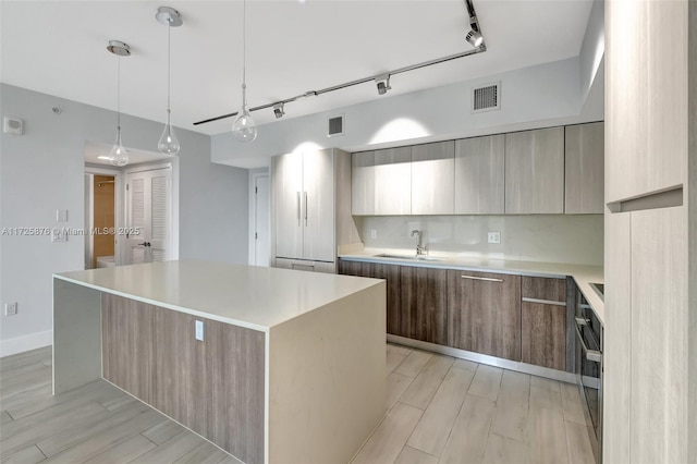 kitchen featuring pendant lighting, a center island, rail lighting, backsplash, and sink