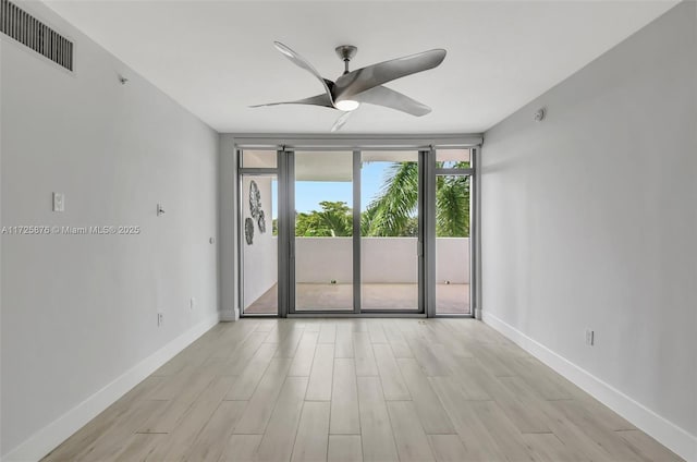 empty room featuring ceiling fan, floor to ceiling windows, and light hardwood / wood-style flooring