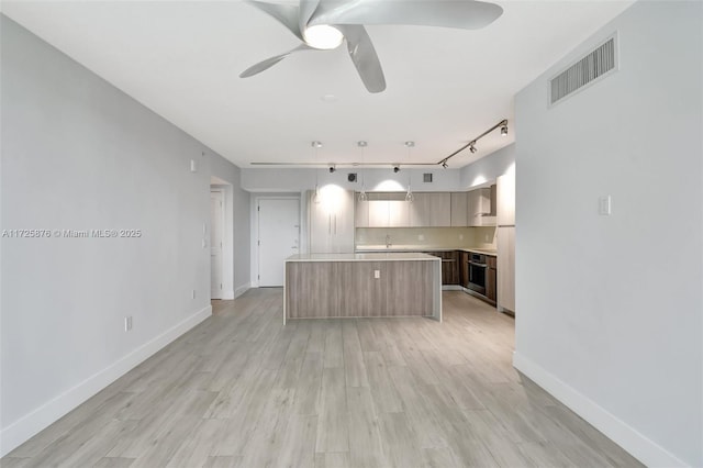 kitchen with stainless steel oven, a center island, light hardwood / wood-style flooring, track lighting, and pendant lighting