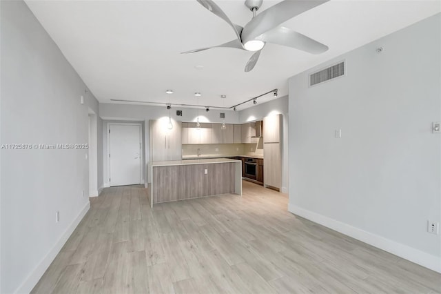 kitchen with oven, ceiling fan, track lighting, a kitchen island, and pendant lighting