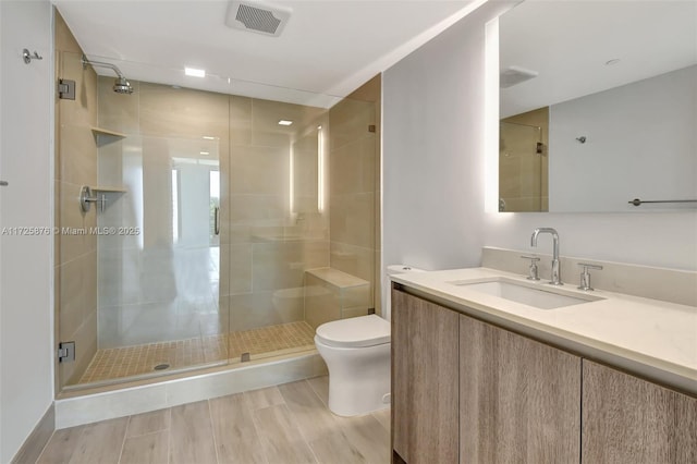 bathroom with vanity, a shower with shower door, and toilet