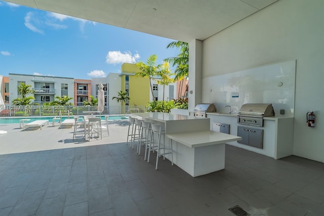 view of patio featuring a community pool, area for grilling, and a wet bar