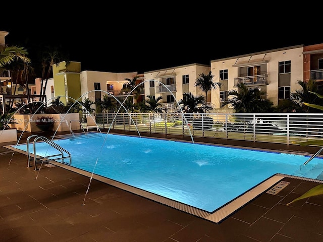 pool at twilight featuring pool water feature