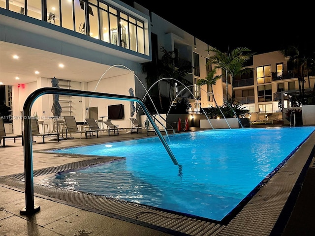 pool at twilight featuring pool water feature