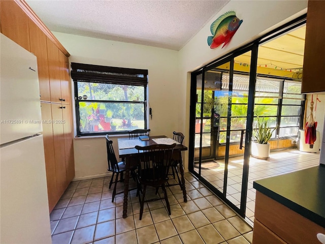 tiled dining space featuring a textured ceiling and french doors