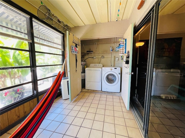 washroom featuring separate washer and dryer, water heater, and light tile patterned flooring