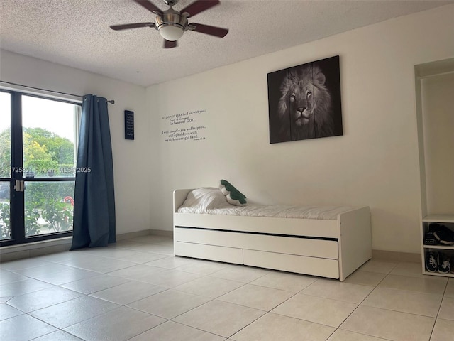 unfurnished bedroom featuring a textured ceiling, ceiling fan, and light tile patterned floors