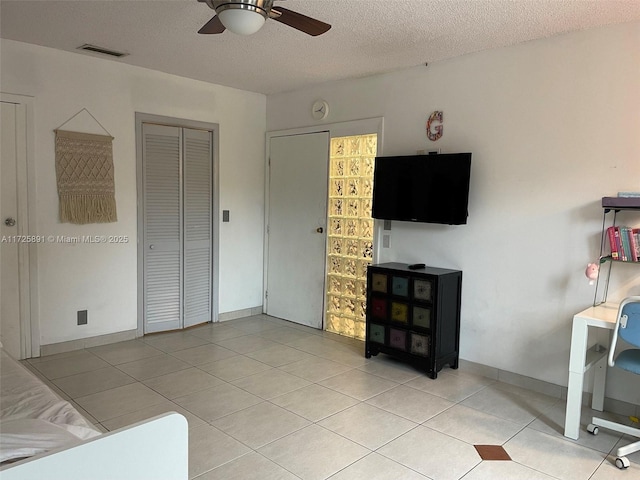 tiled living room featuring a textured ceiling and ceiling fan