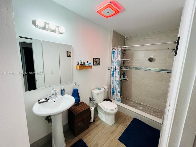 bathroom with a shower with curtain, toilet, and wood-type flooring