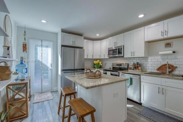 kitchen with light stone countertops, white cabinetry, light hardwood / wood-style flooring, and stainless steel appliances