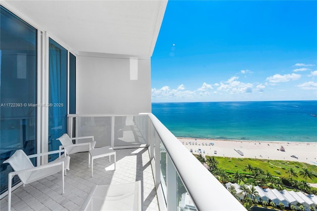 balcony featuring a view of the beach and a water view